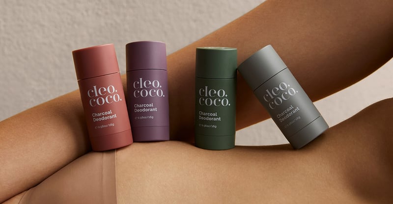 Four tubes of Cleo+Coco deodorant lined up on the side of someone's body.